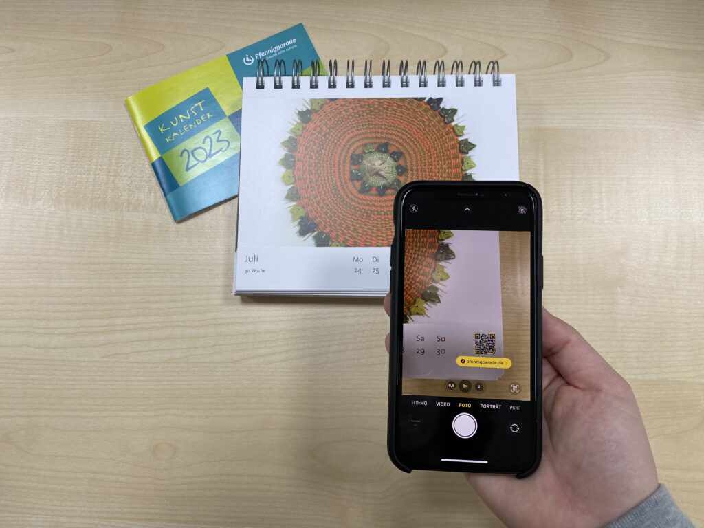 Mit dem Handy den QR Code vom Kunstkalender scannen.