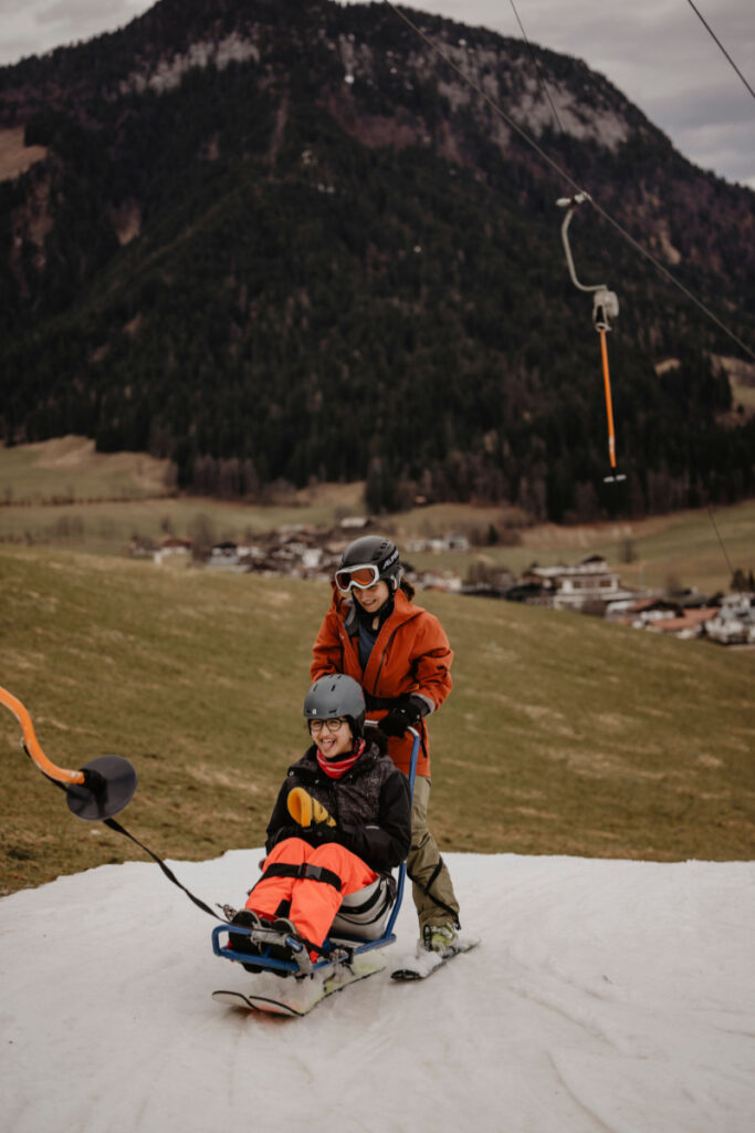 Zwei Personen vor Hügellandschaft in Skiausrüstung