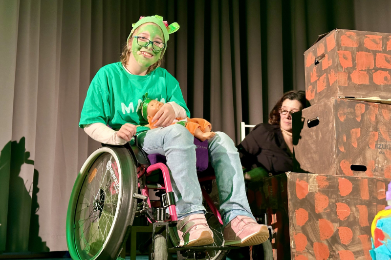 Mädchen im Rollstuhl neben Theaterrequisite