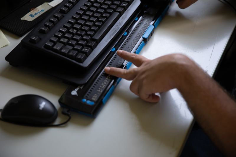 Person arbeitet an Computer mit Brailezeile