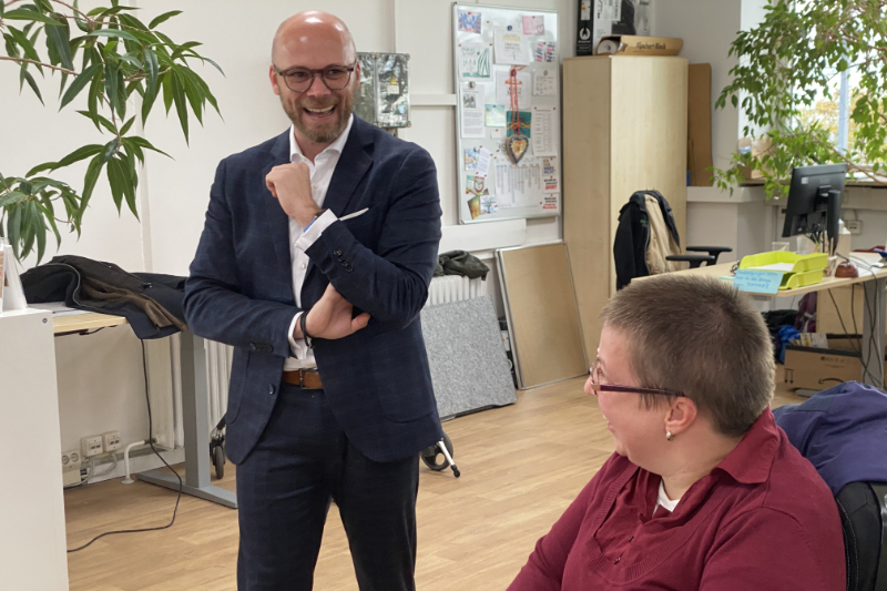 Staatsminister für Digitales Dr. Fabian Mehrin und Werkstattbeschäftigte lächen sich an