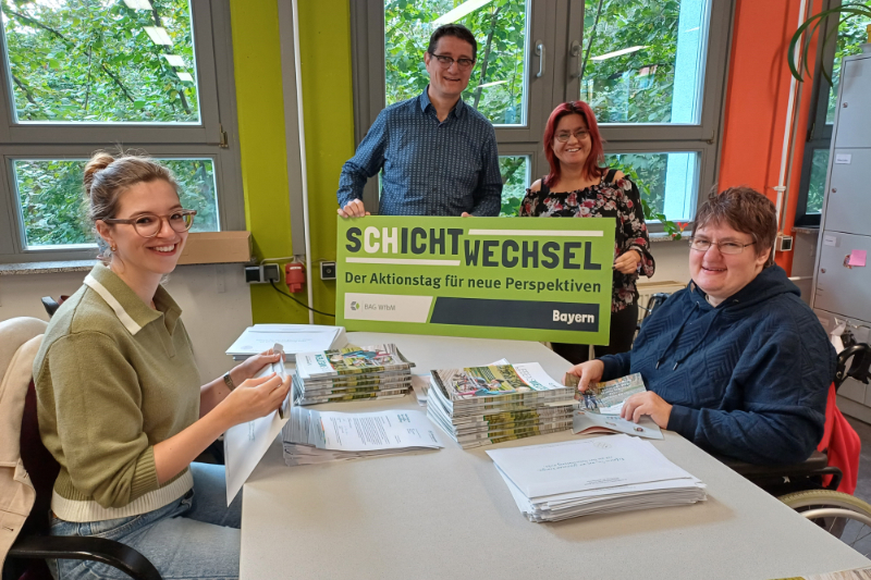 Mehrere Personen an einem Tisch mit Briefumschlägen und Broschüren. Text Schichtwechsel Der Aktionstag für neue Perspektiven BAG WfbM Bayern