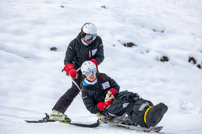 Zwei Personen mit Skibob im Schnee
