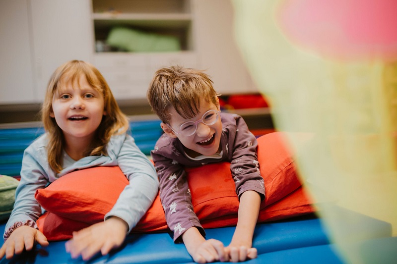 Zwei Kinder liegend auf Kissen und Matten.