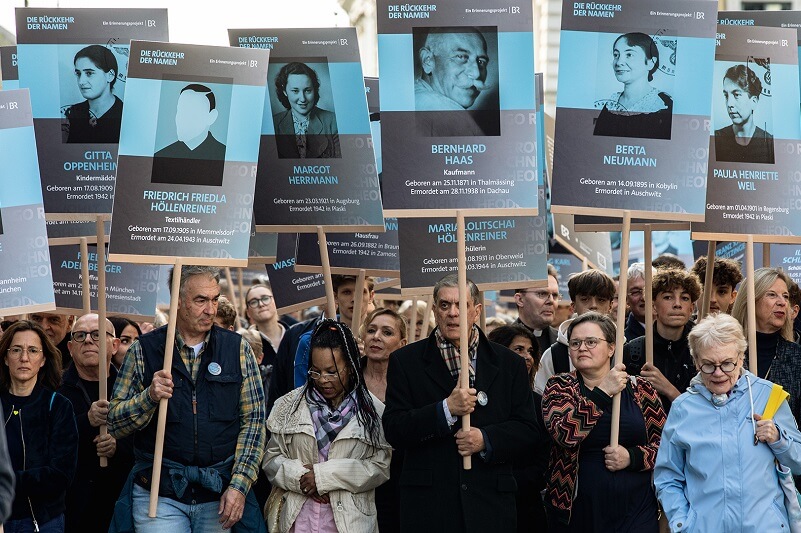 Menschen halten im Rahmen der Aktion "Rückkehr der Namen" Schilder mit Namen vom Naziregime ermordeter Personen hoch.