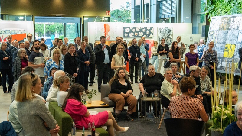 Viele Personen, sie sich auf einer Ausstellung von Bildern befinden.