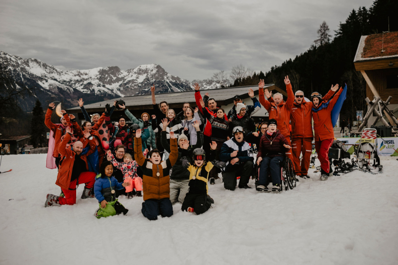 Viele Personen nebeneinander vor Servicehaus und Alpenkulisse