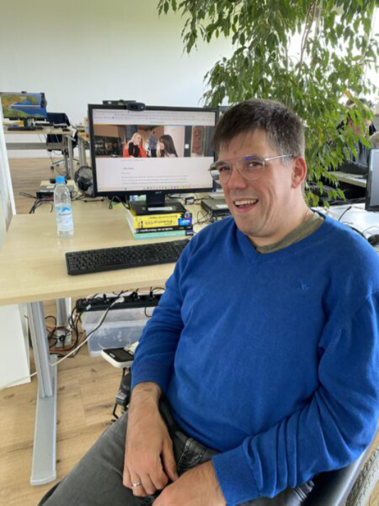 Mann im Rollstuhl an Computerarbeitsplatz. Auf dem Monitor Seite Museen