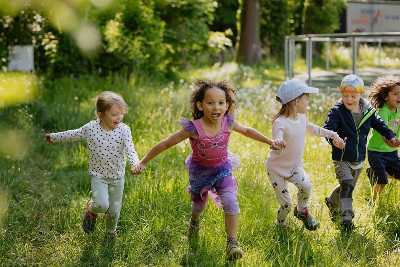 Kinder laufen Hand in Hand über eine Wiese