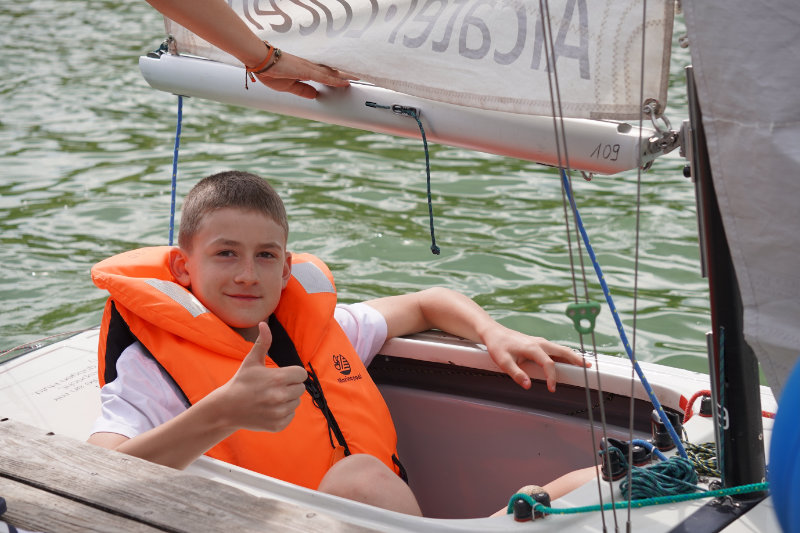 Junge mit Rettungsweste in Segelboot auf Ammersee