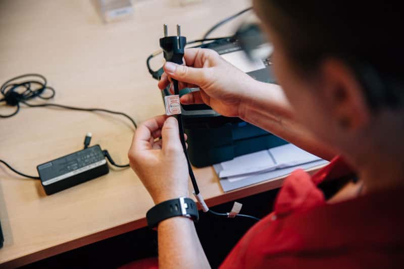Person prüft Stecker und Ladegerät an Tisch