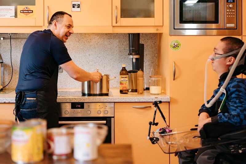 Woo mit einem Betreuer in der Küche beim Kochen: damit es weitergeht!