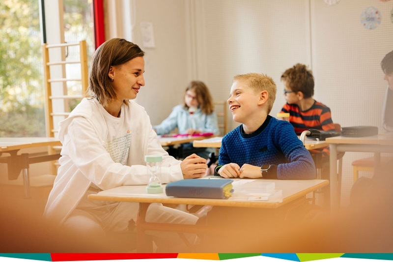 Lehrerin und Schüler nebeneinander in Klassenzimmer