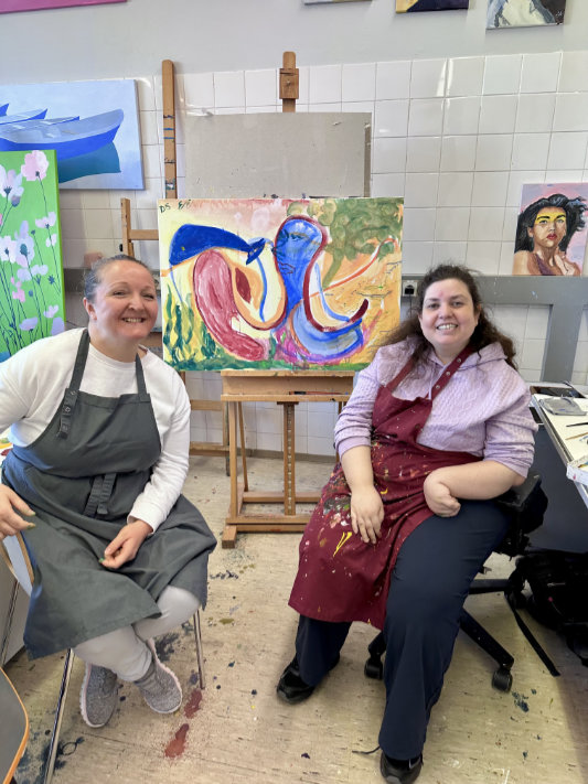 Zwei Personen im Atelier vor Kunstwerken