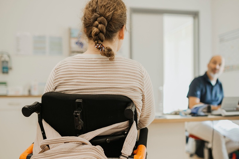 Medizinische Versorgung von Menschen mit Behinderung in München: Patientin in Rollstuhl bei Arztsprechstunde