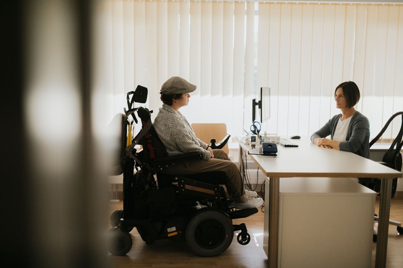 Medizinische Versorgung von Menschen mit Behinderung in München: Patientin in Rollstuhl bei Sprechstunde mit Ärztin