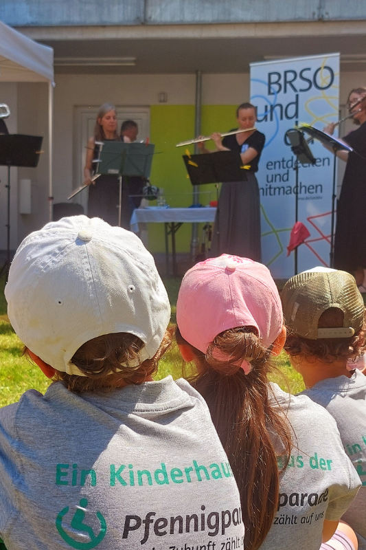 Drei Kinder schauen auf Bühne mit Musikern und Instrumenten