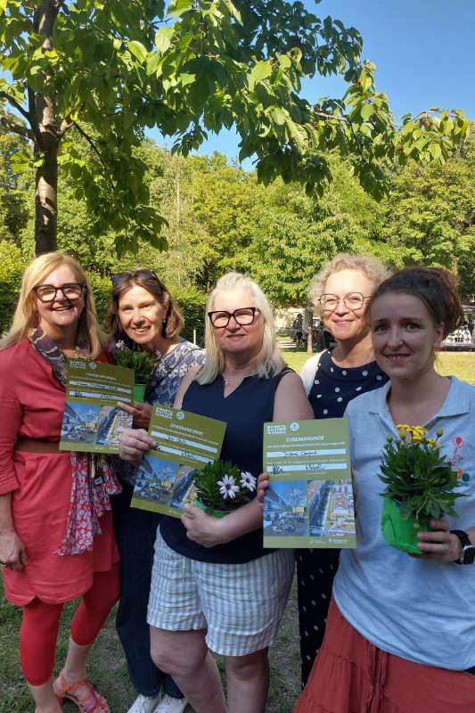 Mehrere Personen stehen mit Plakat in der Hand nebeneinander. Eine hat einen Blumenstrauß in der Hand