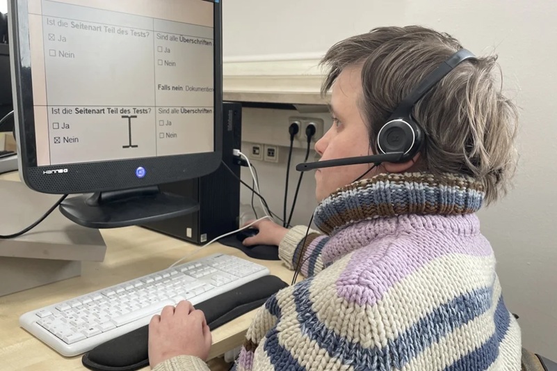 Person mit Headeset vor Computer-Monitor