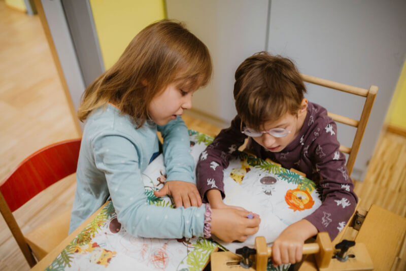 Zwei Kinder sitzen an einem Tisch und malen