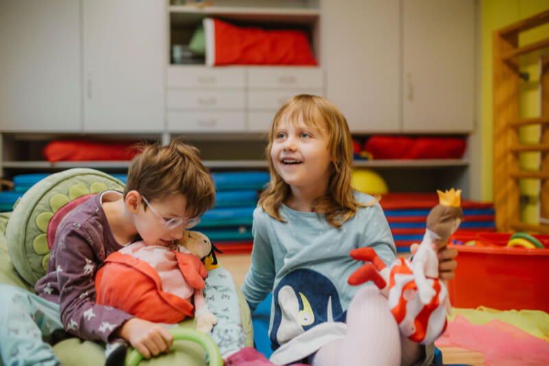 Zwei Kinder in Turnraum mit Stofftieren