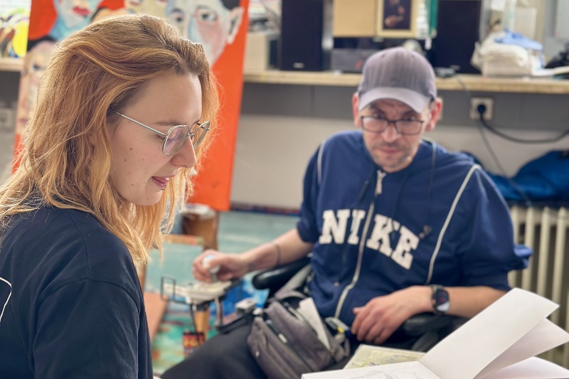 Zwei Personen mit und ohne Rollstuhl im Atelier