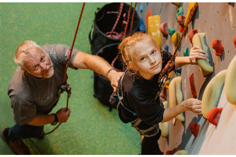 Mädchen mit Trainer an Kletterwand