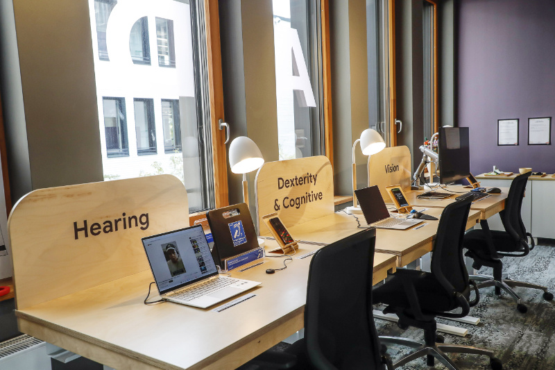 Arbeitsplatz mit mehreren digitalen Kommunikationsmitteln Text: Hearing Dexterity & Cognitive & Vision