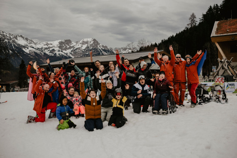 Viele Personen nebeneinander vor Servicehaus und Alpenkulisse