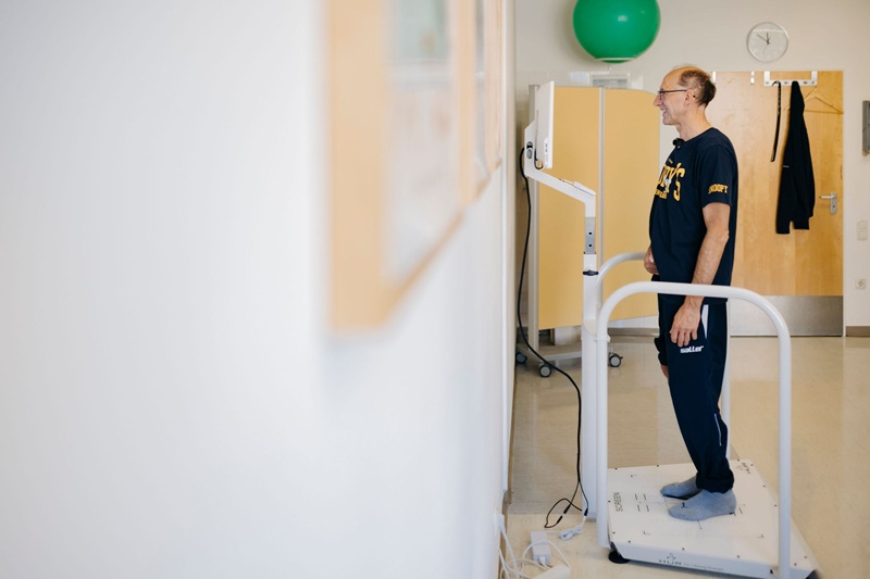 Patient steht auf Therapiegerät