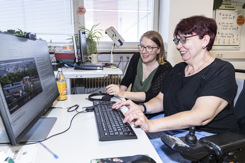Zwei Frauen sitzen an einem Schreibtisch vor einem Bildschirm