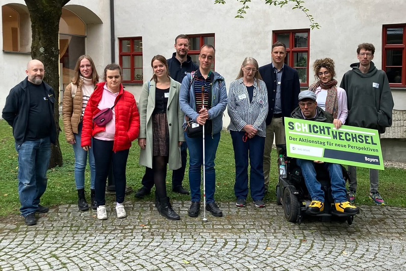 11 Personen mit und ohne Behinderung der Pfennigparade, der Isar-Würm-Lech Werkstätten (IWL) und des Landratsamtes München vor einem Gebäude