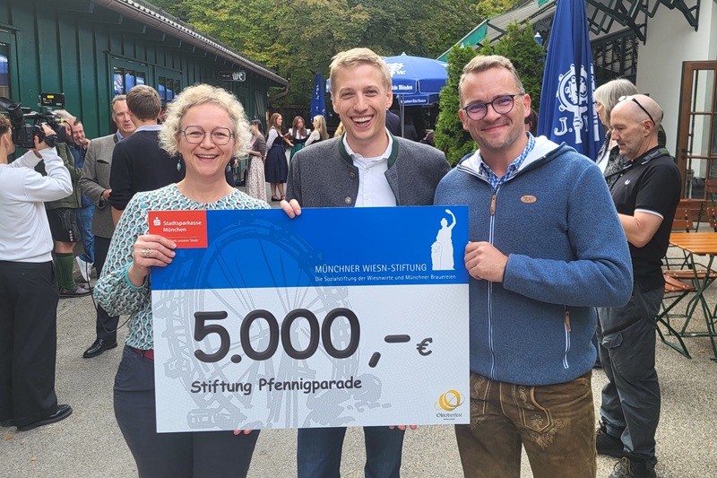 Susanne Schönwälder, Münchner Oberbürgermeister Dominik Krause und Wolfgang Schreiter halten einen Spendencheck für die Stiftung Pfennigparade in Höge von 5.000 Euro.